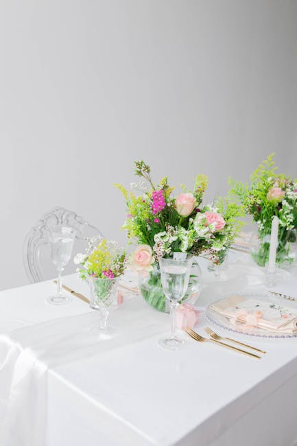 A minimalist wedding table setting with natural linen, candlelight, and single-variety flowers in clear glass